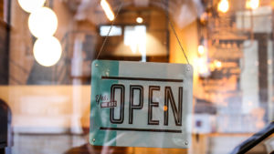 Photograph of an open sign displayed in the window of a brick and mortar store, used as the feature image for a blog post about customer testimonials.